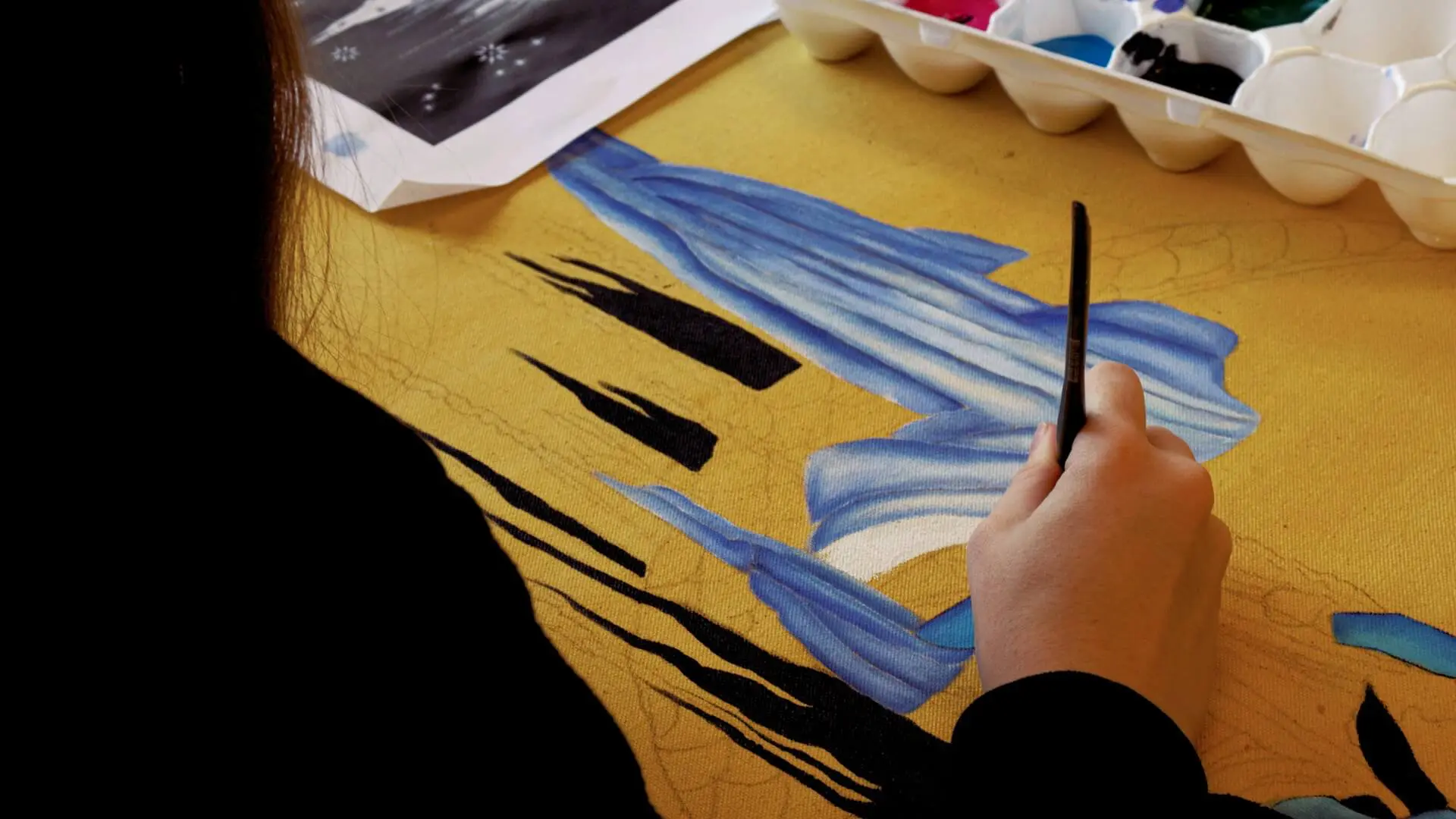 Young adult painting to represent building creative projects in your 20s as a valuable personal investment.