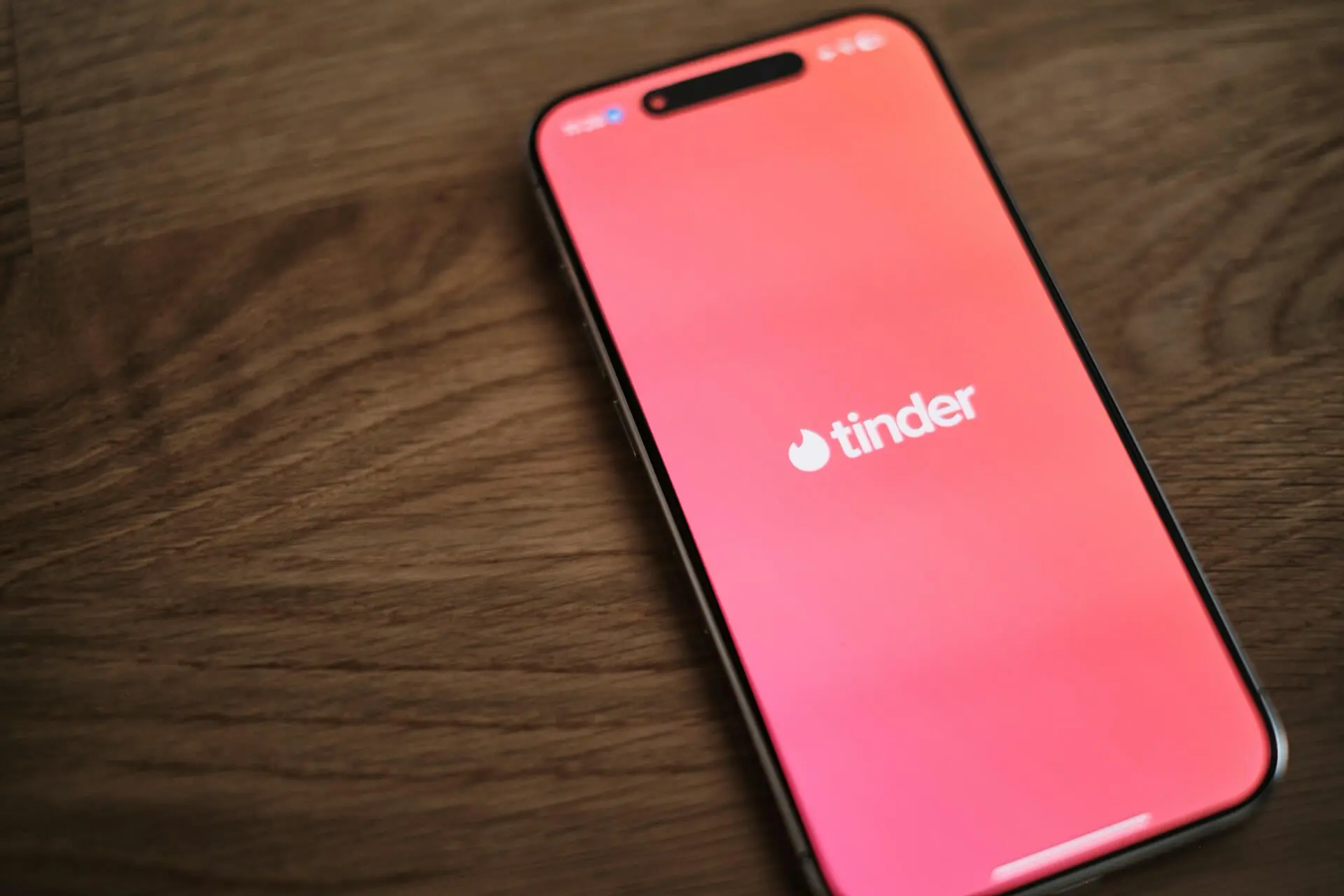 An iPhone showing the Tinder app on a wooden table, symbolizing modern dating culture.