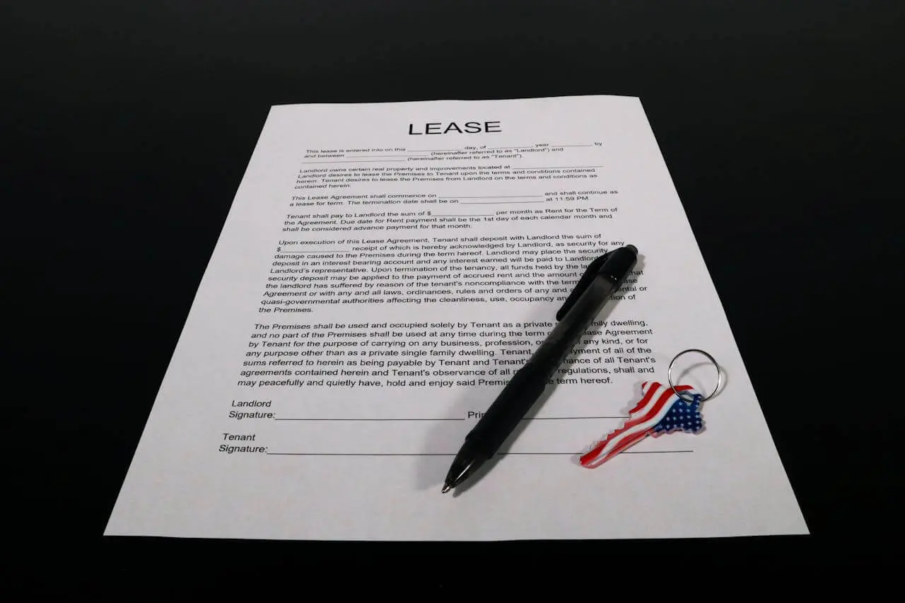 Close-up of a lease agreement on a table with a pen and house key, symbolizing signing a first apartment lease and reviewing rental terms carefully.