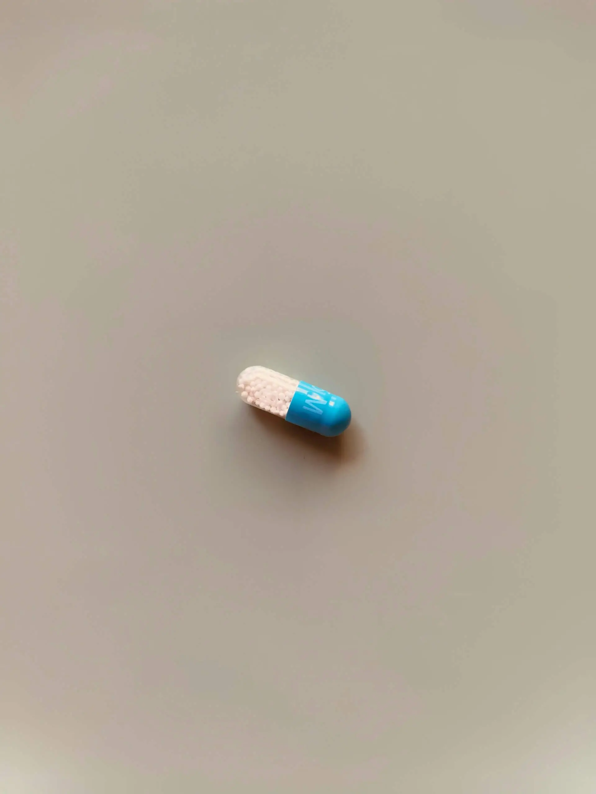 A single blue and white capsule on a neutral background, symbolizing the idea that relationships aren’t a magic pill that fixes personal issues.
